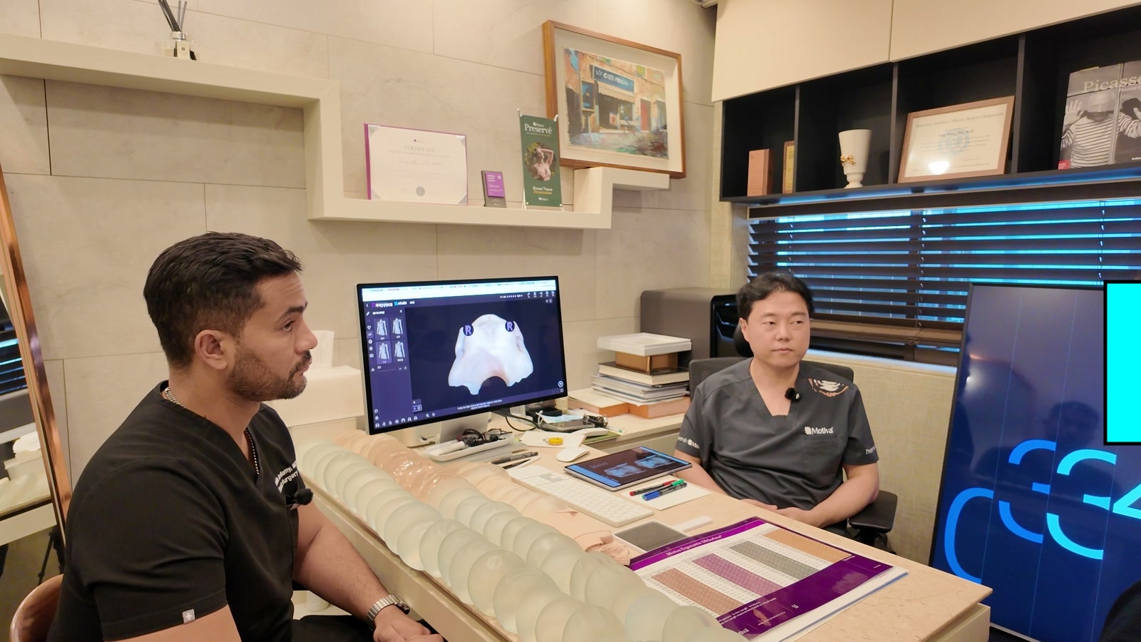 Dr. Bellamy and Dr. Choi discussing breast augmentation at a consultation desk
